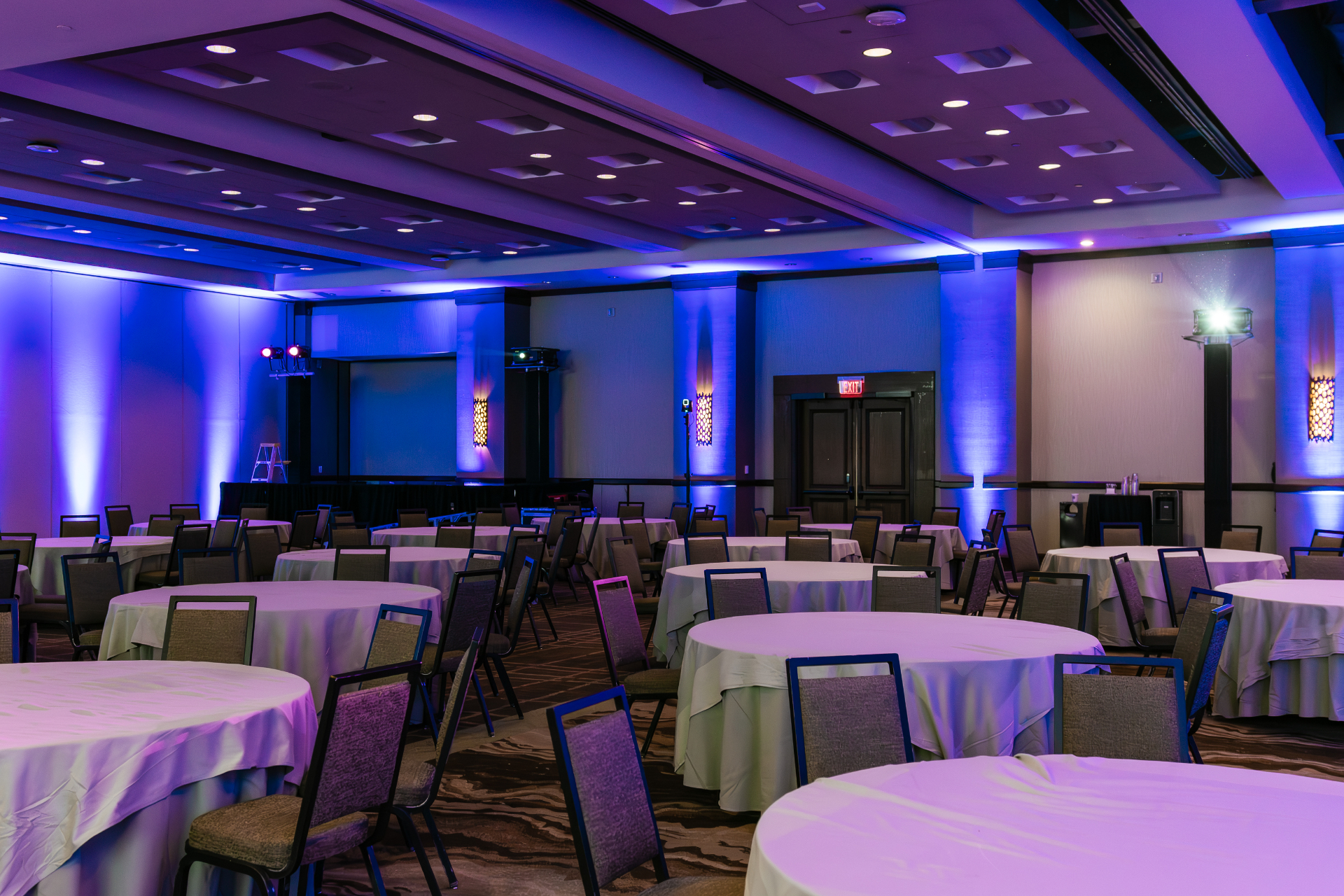 Corporate ballroom with blue uplighting and stage presentation setup